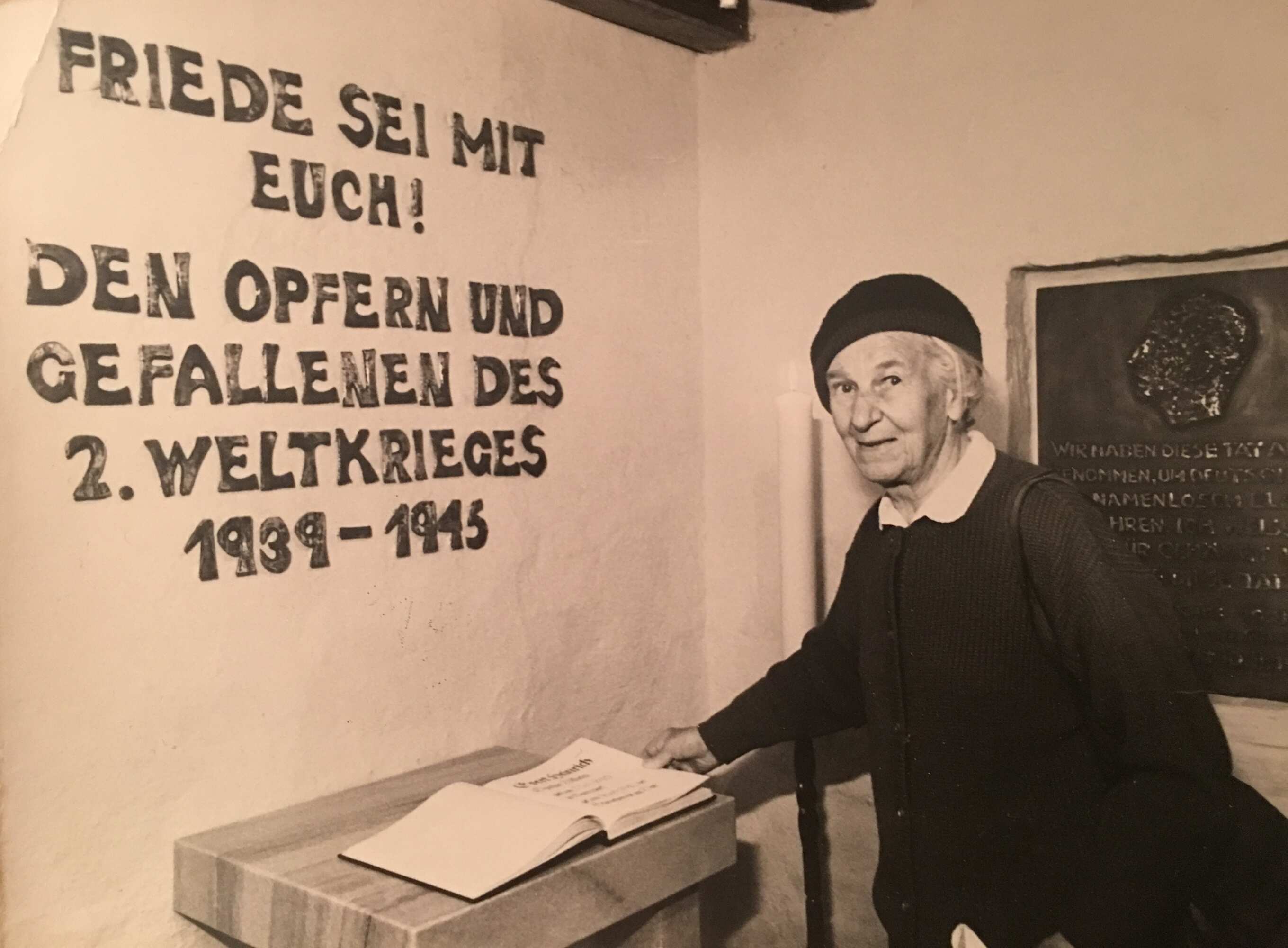 6 Tisa von der Schulenburg in der nahegelegenen Gressower Dorfkirche, hinter ihr die Gedenkplatte, die sie für ihren Bruder angefertigt hat.